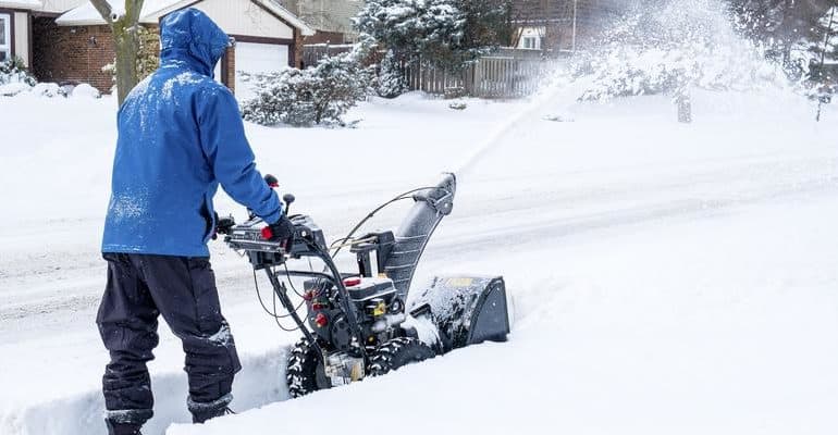 G & M employee pushing snow blower through deep snow